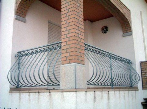 Un balcone con ringhiera in ferro battuto e colonna in mattoni