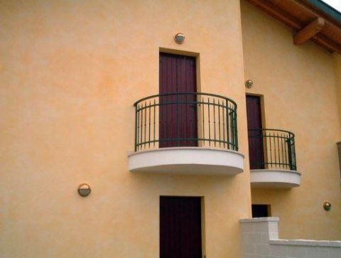 Un edificio giallo con un balcone e una porta