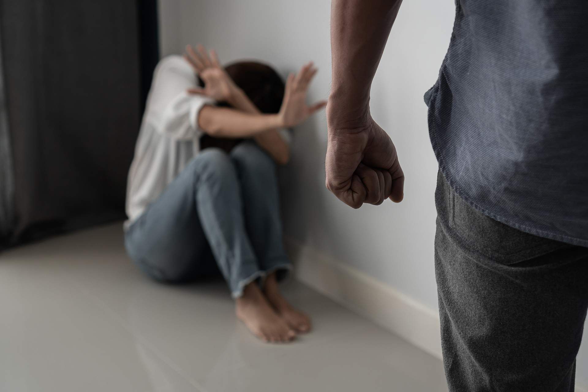 A man is standing next to a woman sitting on the floor.