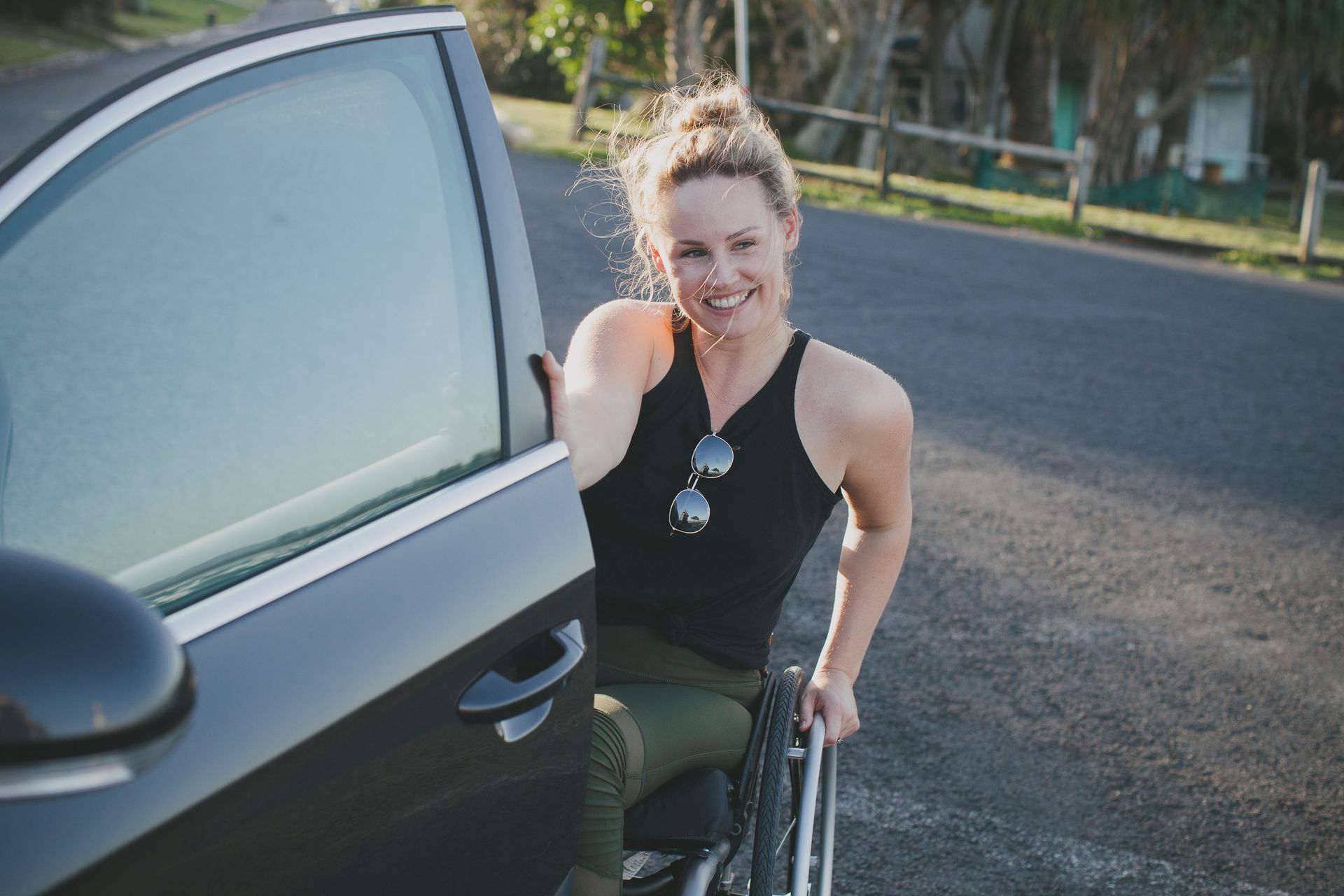 A woman in a wheelchair is getting out of a car.