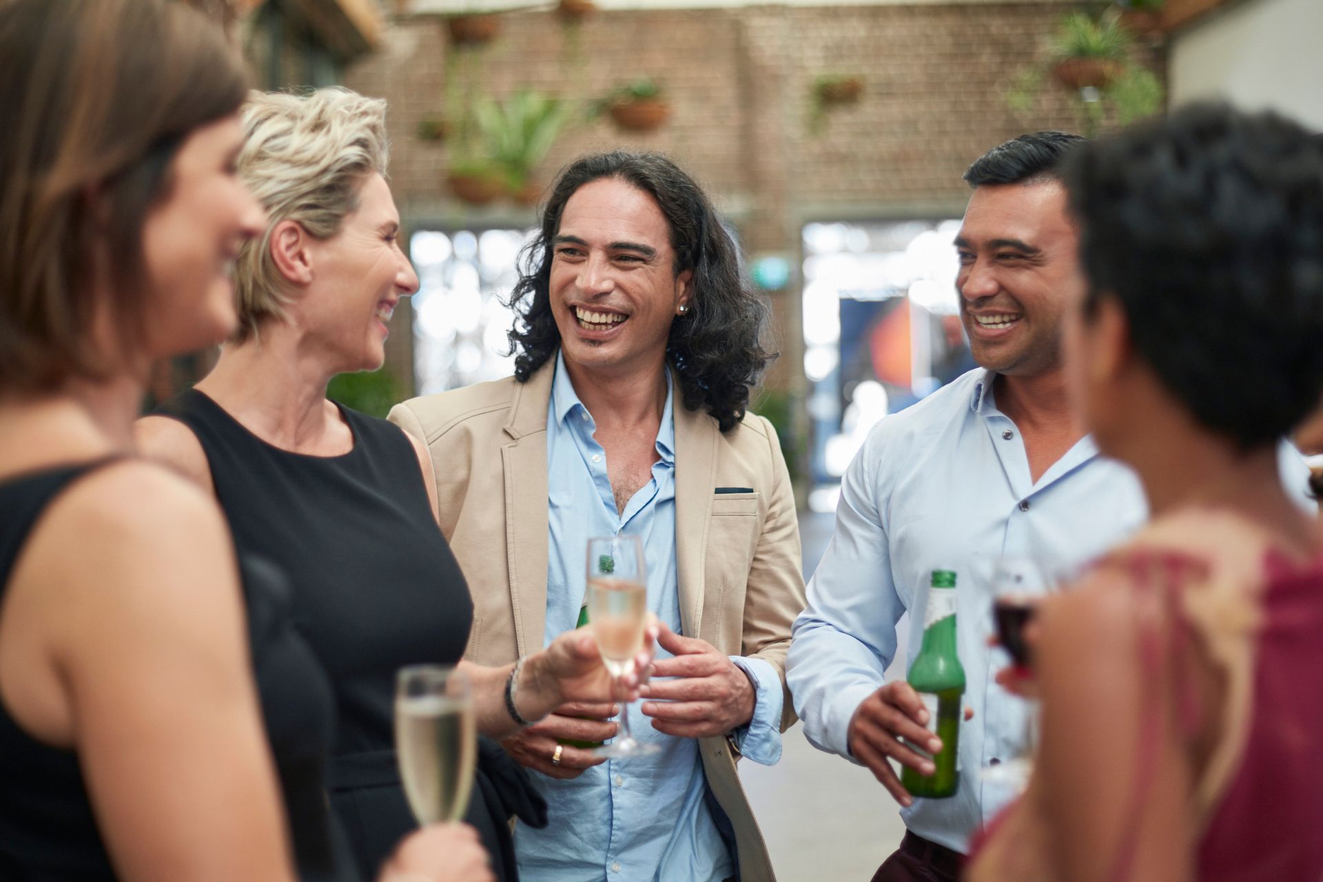 A group of people are standing around drinking champagne and beer.