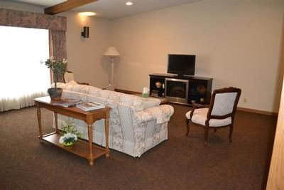 Living room with white sofa, TV, armchair, and wooden table on brown carpet
