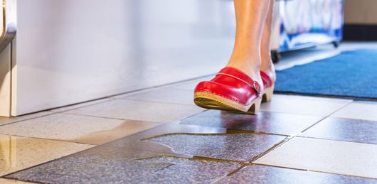 A woman in Connecticut walking on a tiled floor that looks slippery and needs a slip preventive treatment.