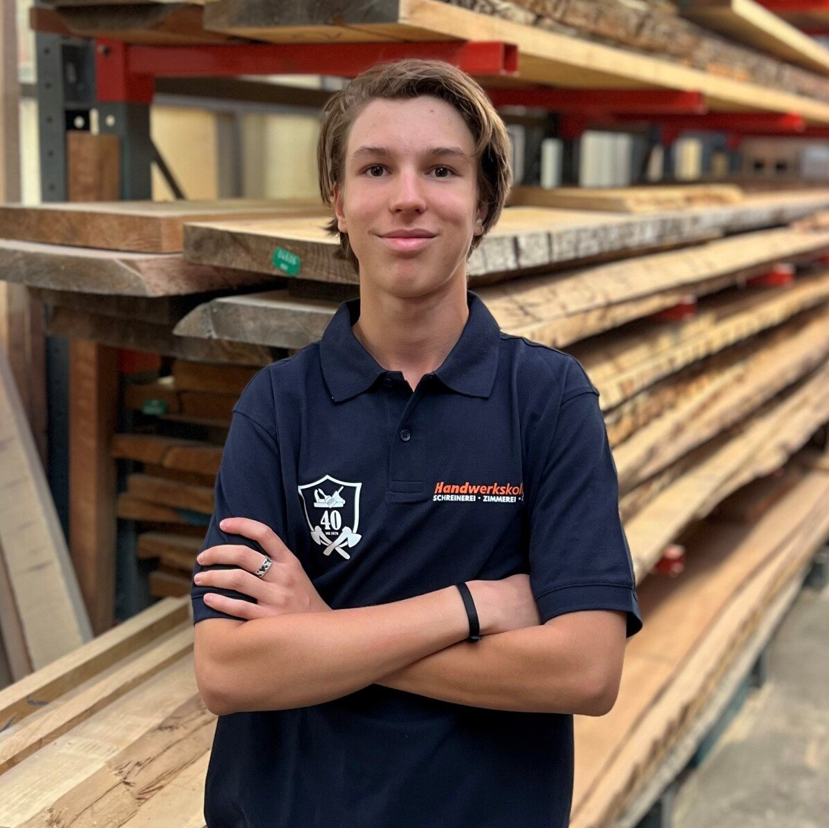 Ein junger Mann steht vor einem Stapel Holz