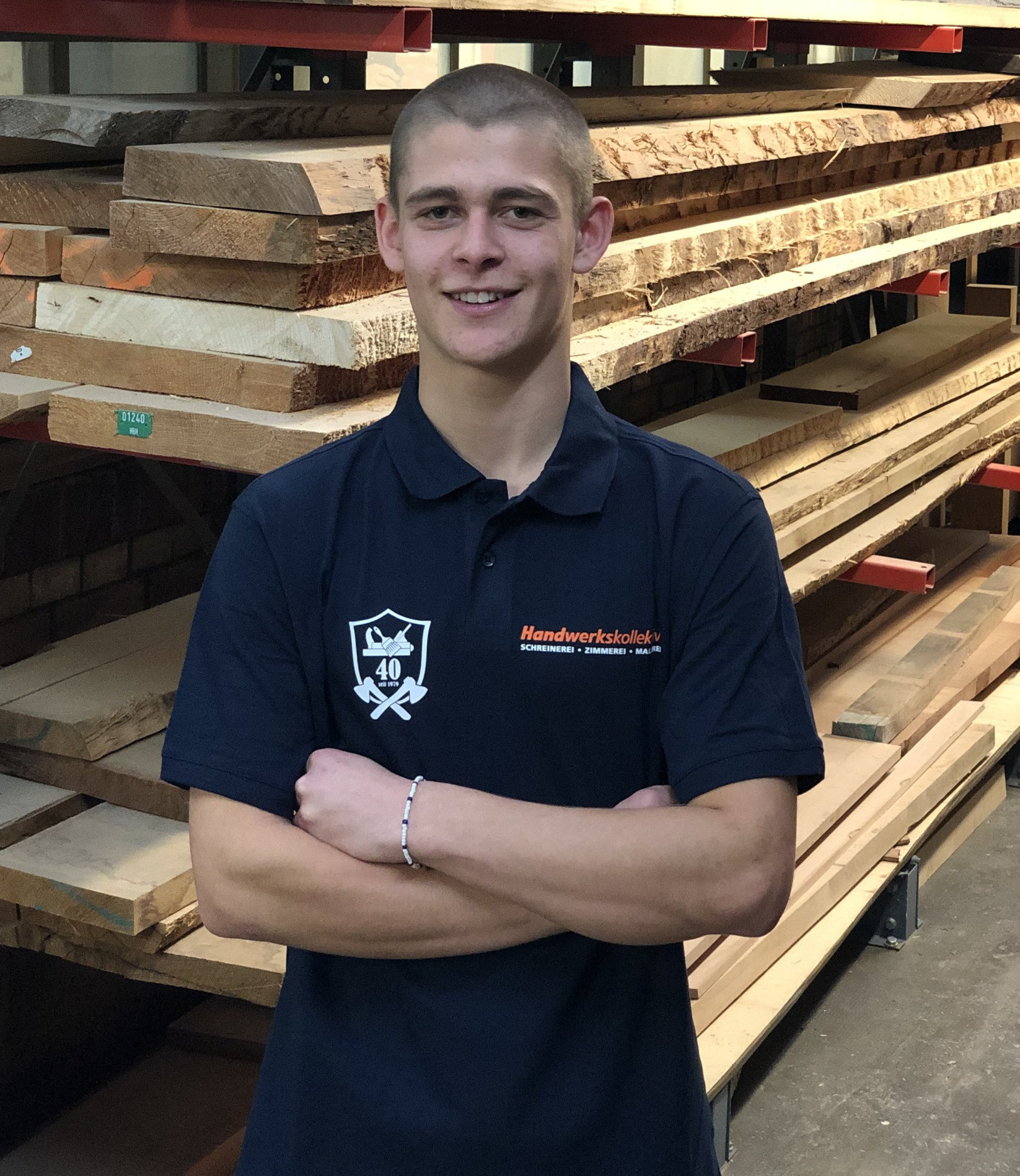 Ein junger Mann steht vor einem Stapel Holz