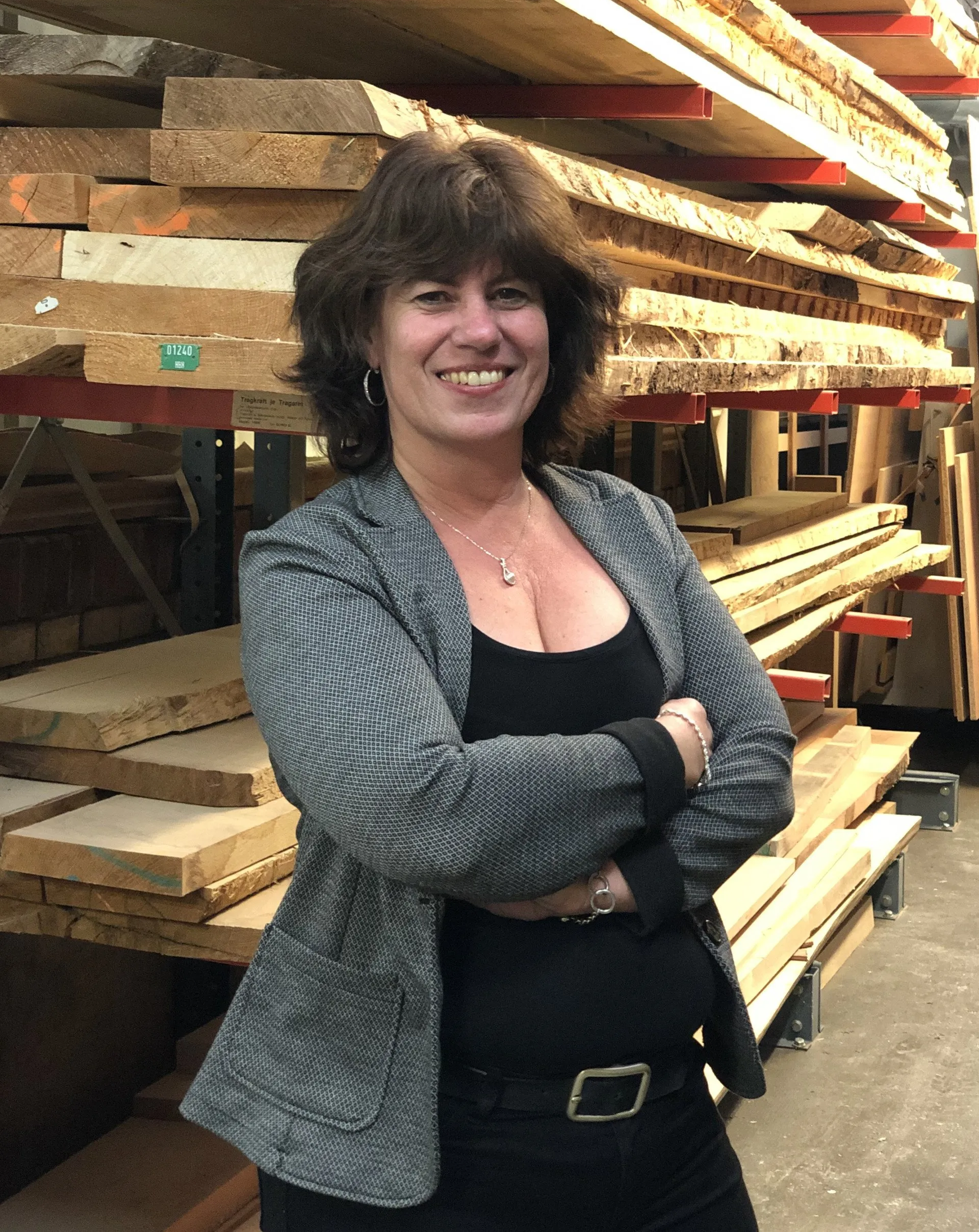 Eine Frau steht vor einem Holzstapel.