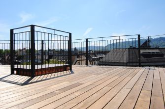 Ein Holzdeck mit einem Metallgeländer und Bergen im Hintergrund.