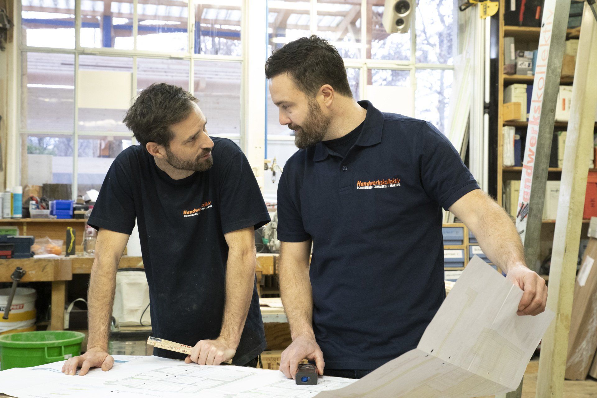 Zwei Männer besprechen einen Plan in einer Werkstatt
