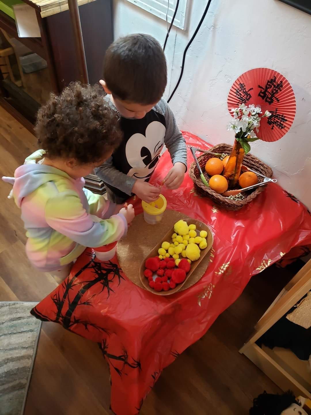 A boy and a girl are sitting at a table playing with toys.