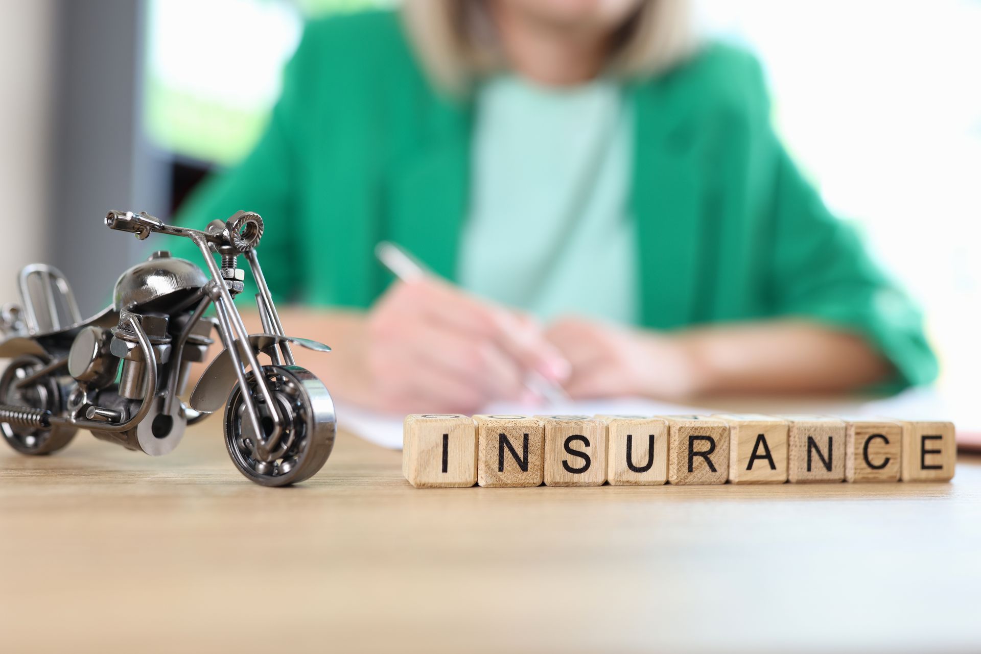 Miniature motorcycle next to wooden blocks spelling