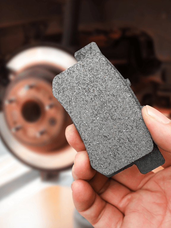 a mechanic holding brake pads for replacement service