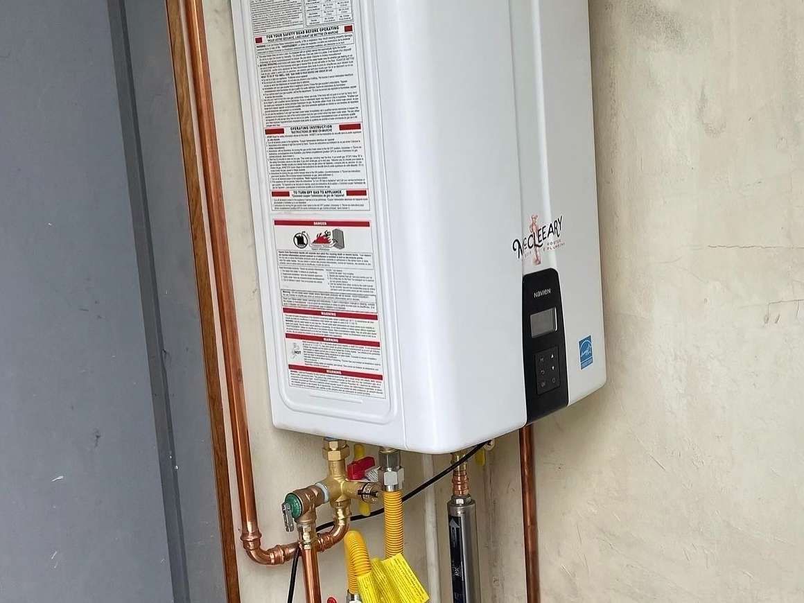 Wall-mounted white water heater with copper pipes in a utility area