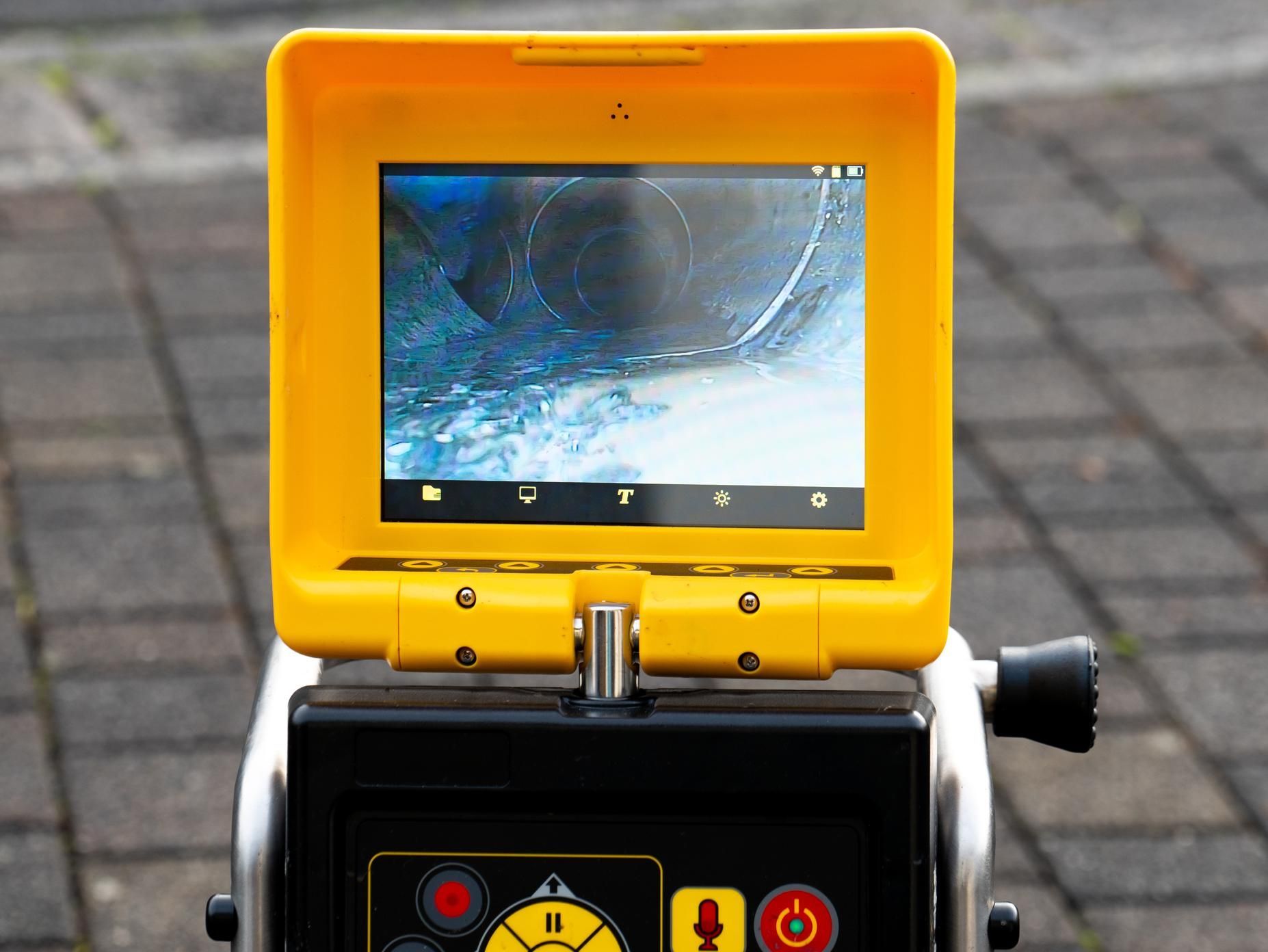 Yellow industrial inspection device with a cracked screen and control panel on a paved surface