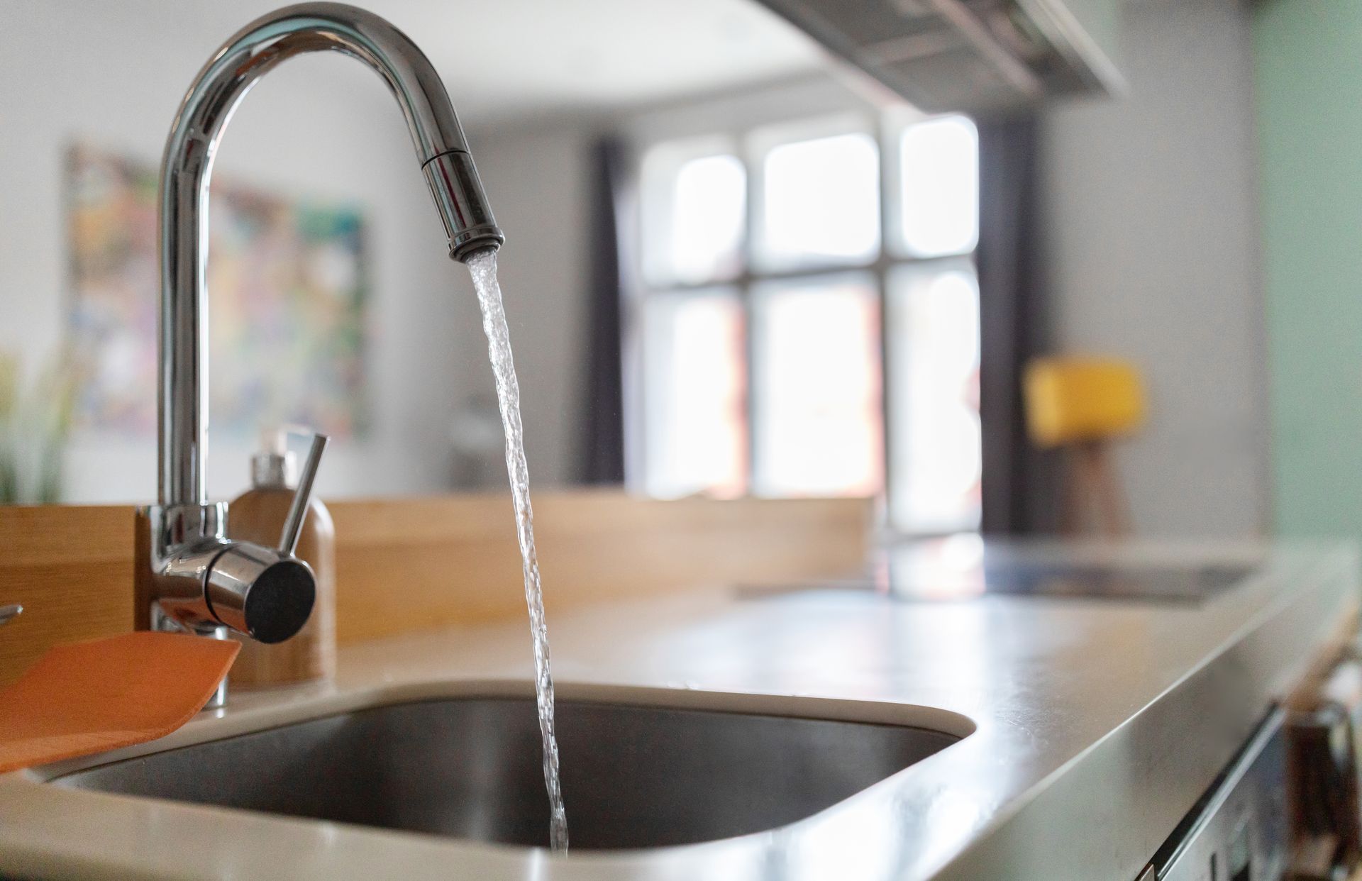 Chrome kitchen faucet running into a stainless-steel sink