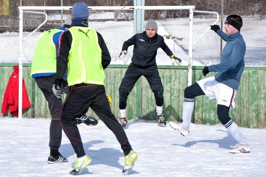A group of men are playing soccer in the snow.