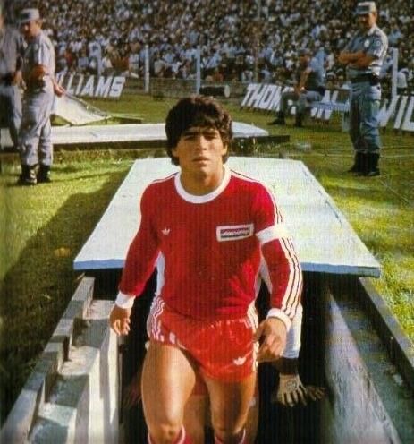 A man in a red shirt and red shorts is walking out of a tunnel.
