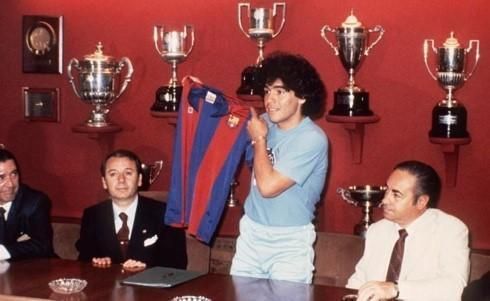 A man is holding a shirt in front of trophies