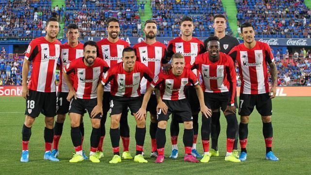 A group of soccer players are posing for a team photo on a field.