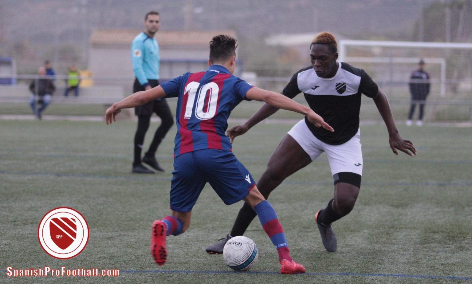 Two soccer players are playing a game of soccer on a field.