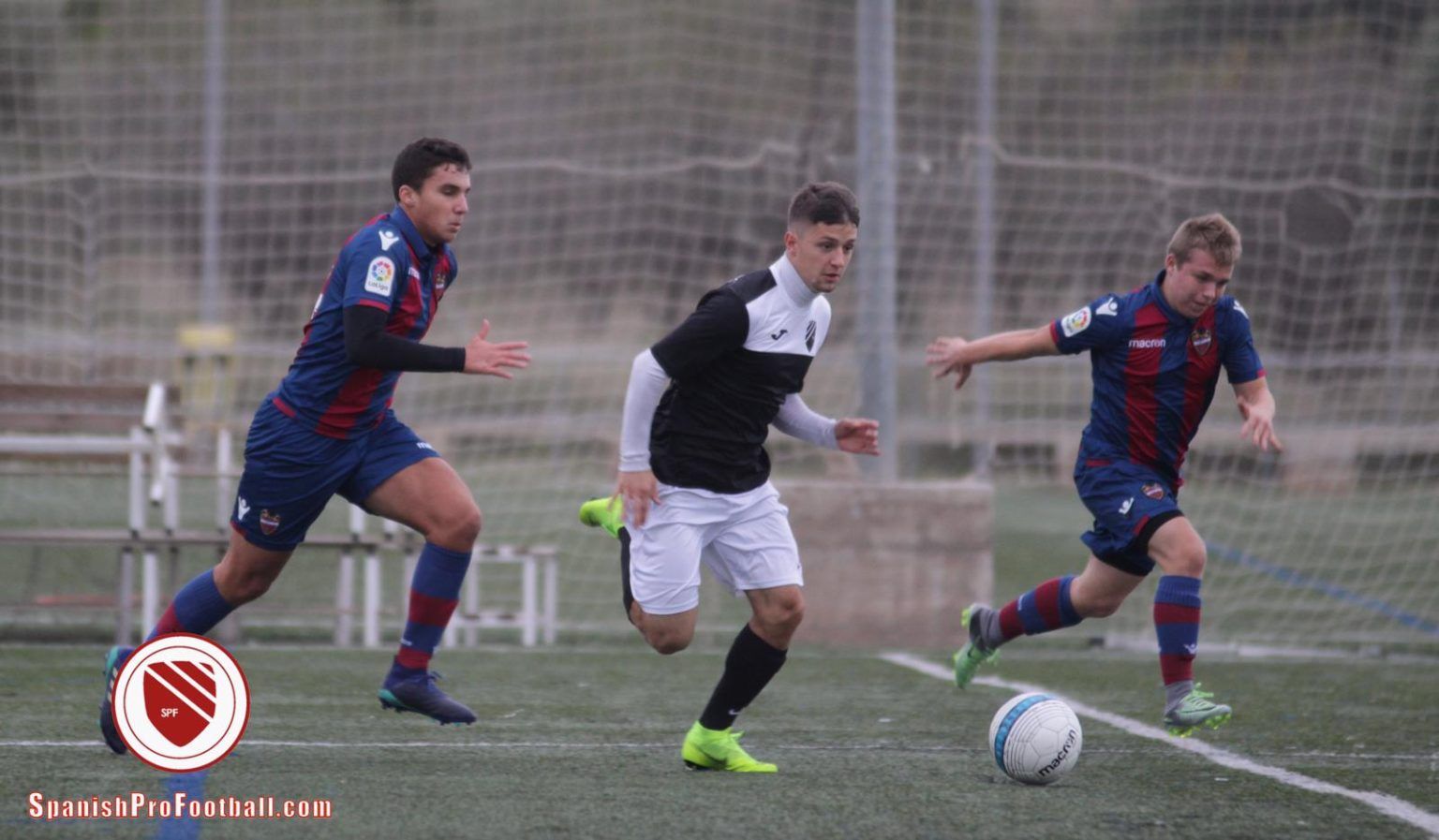 A group of soccer players are playing soccer on a field.