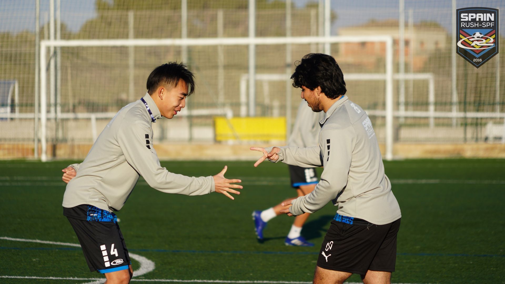 Two soccer players are standing next to each other on a field.