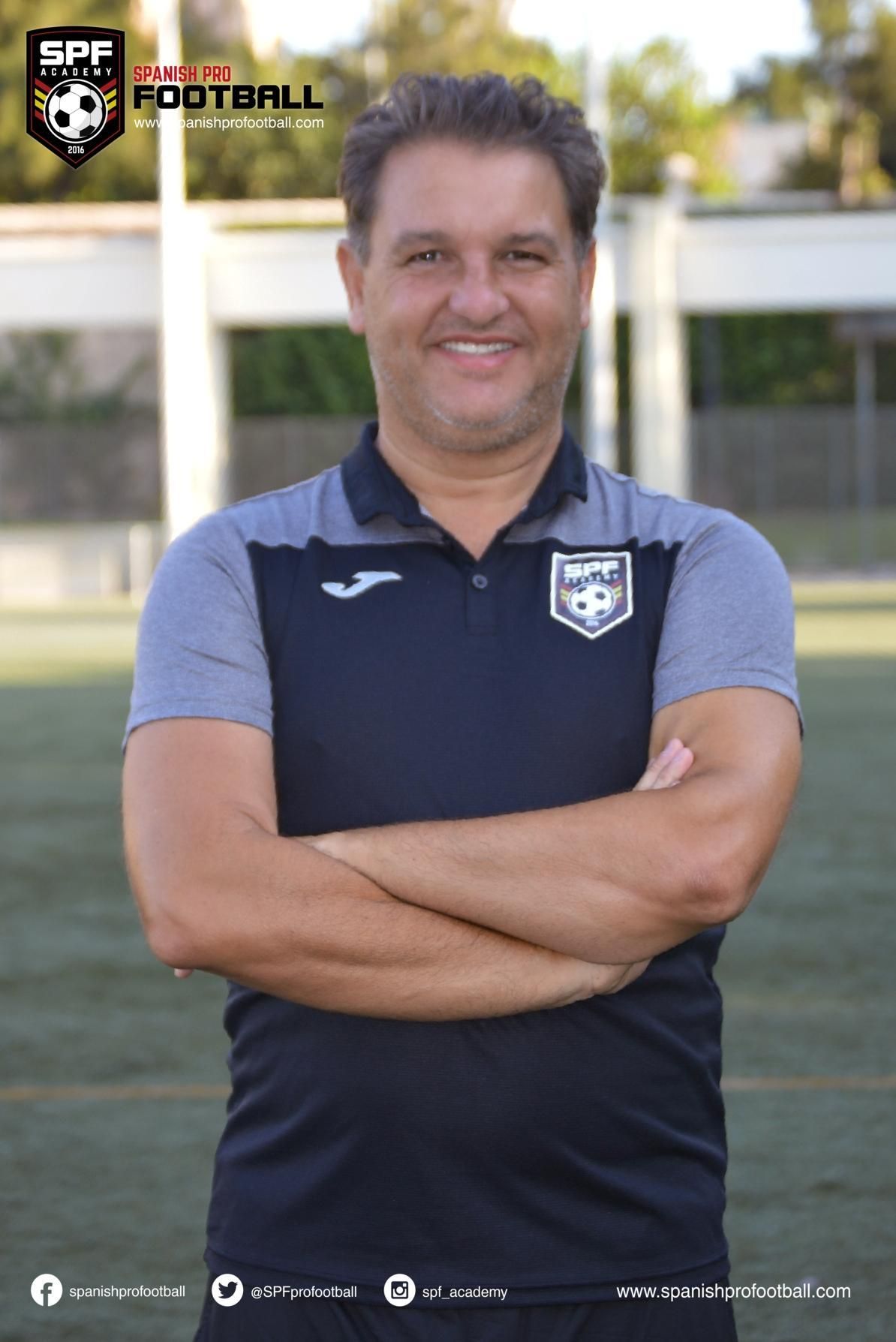 David Sanz posing for a picture with his arms crossed on a soccer field.