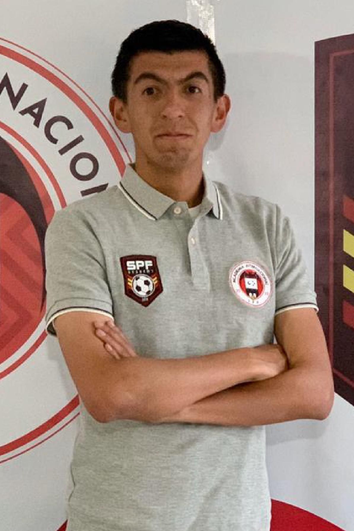 Gabriel Lara with his arms crossed in front of a sign that says nacion