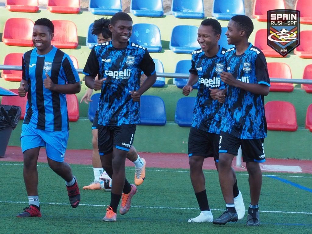 A group of young men are running on a soccer field.