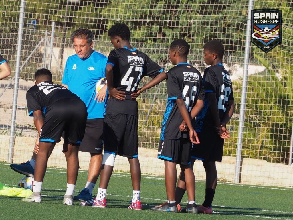 A group of young men are standing on a soccer field talking to each other.