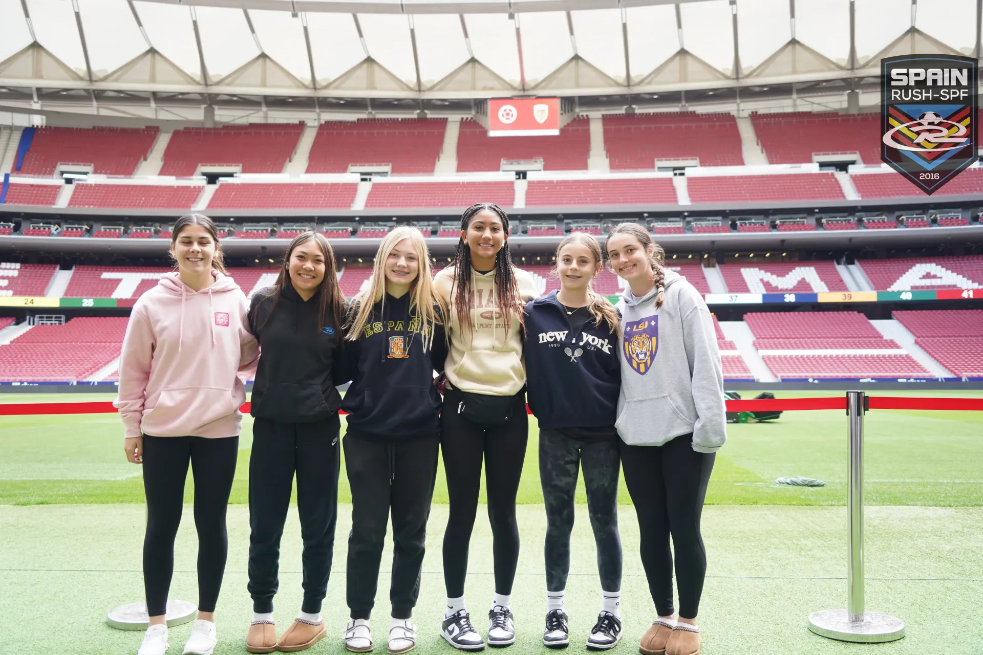 A group of young women are posing for a picture in a stadium.