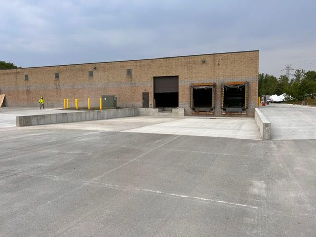 Warehouse loading docks. A person in a vest stands near the concrete loading area.