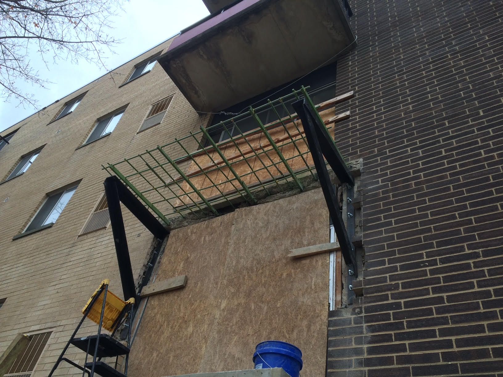 Exterior of a commercial building with a rebuilt balcony, supported by metal and wooden structures.