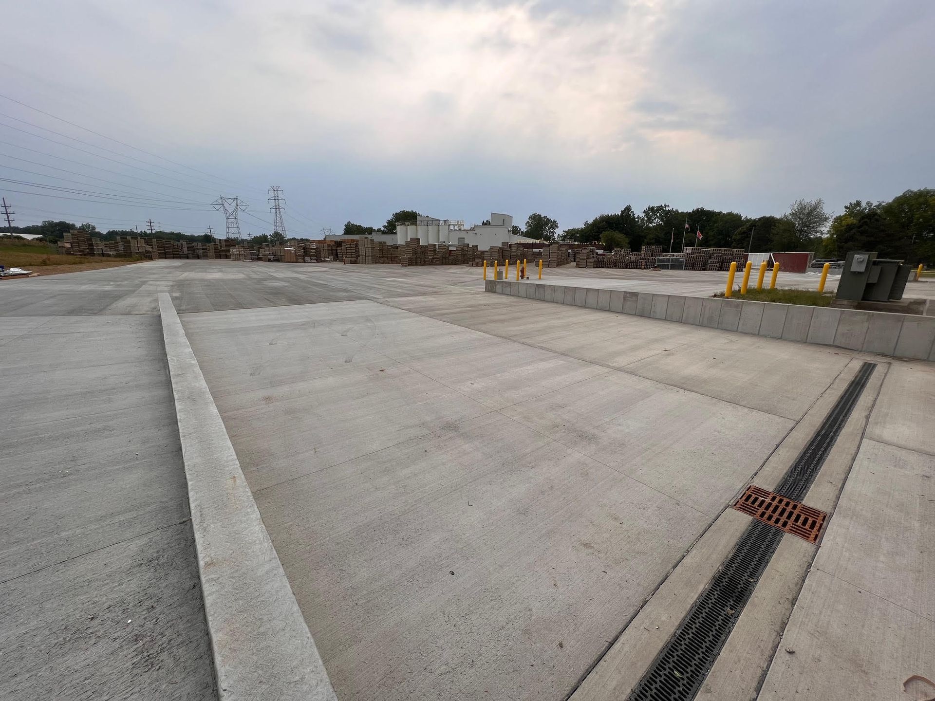 Concrete industrial area with drainage and storage, overcast sky.