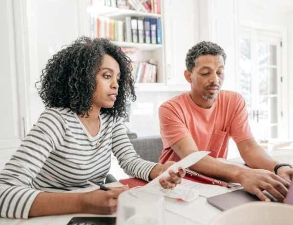A man and a woman are sitting at a table looking at papers.