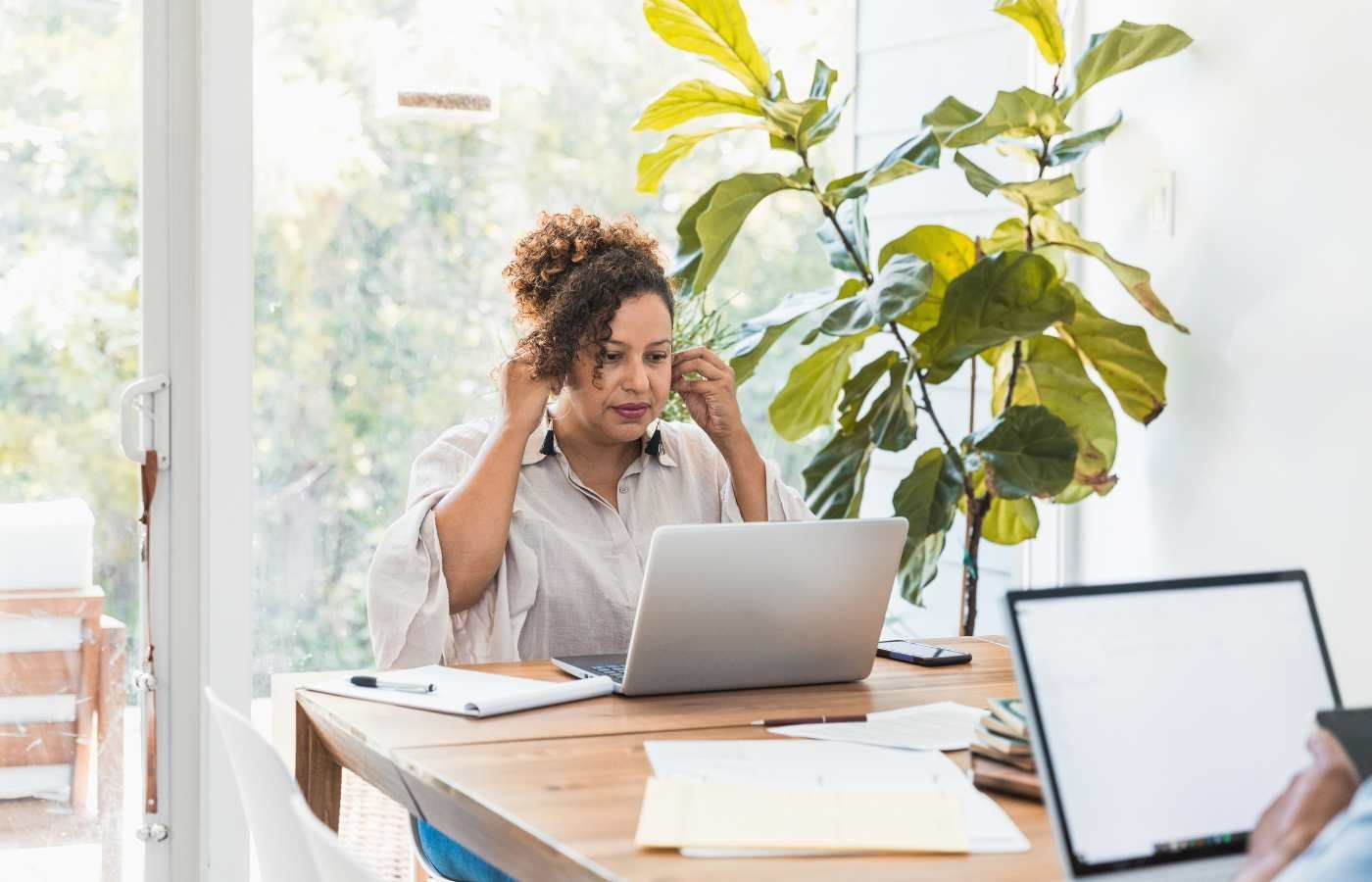 A woman is sitting at a table using a laptop computer.
