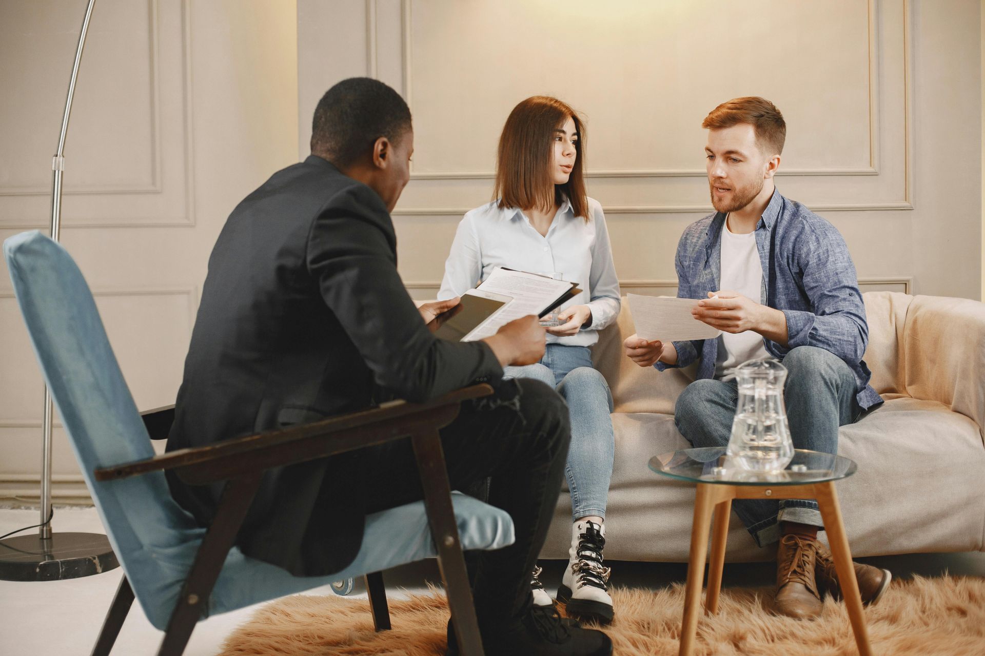 A man and a woman are sitting on a couch talking to a man.
