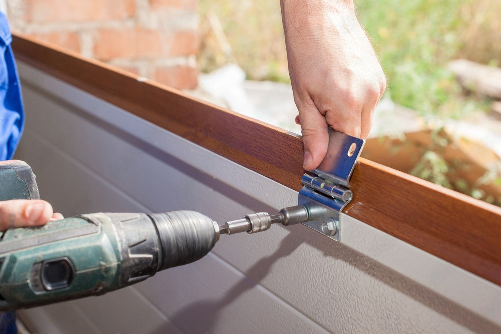 a man is using a drill to install a garage door .