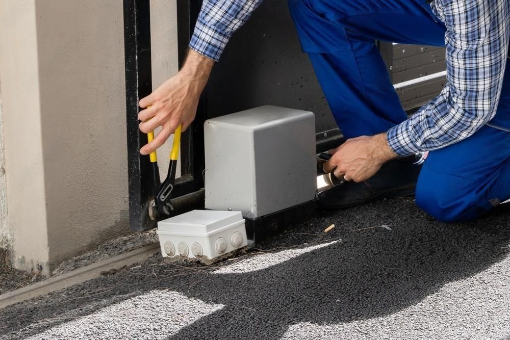 a man is working on a sliding gate with a pair of pliers .
