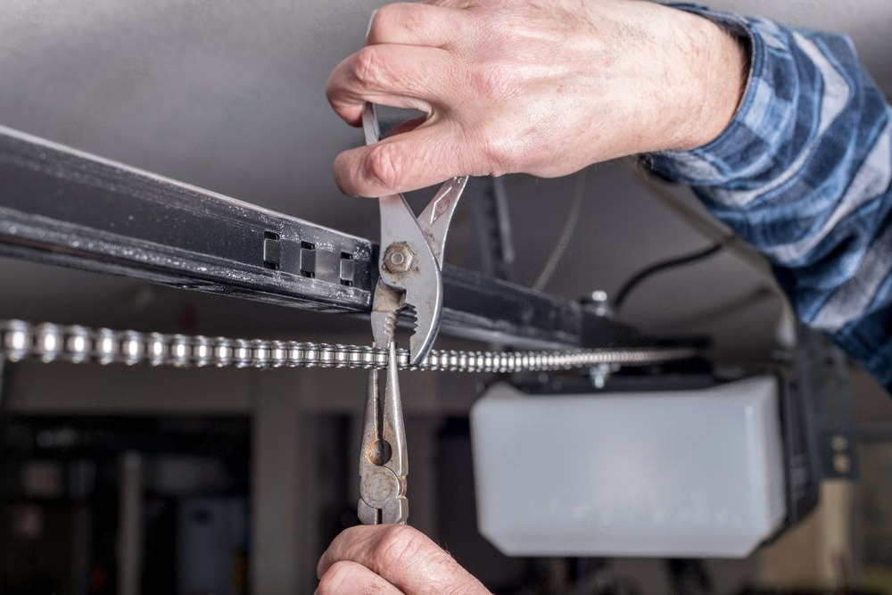 a person is fixing a garage door with a pair of pliers .