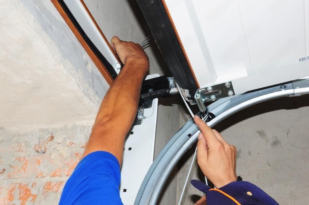 a man is fixing a garage door with a screwdriver .