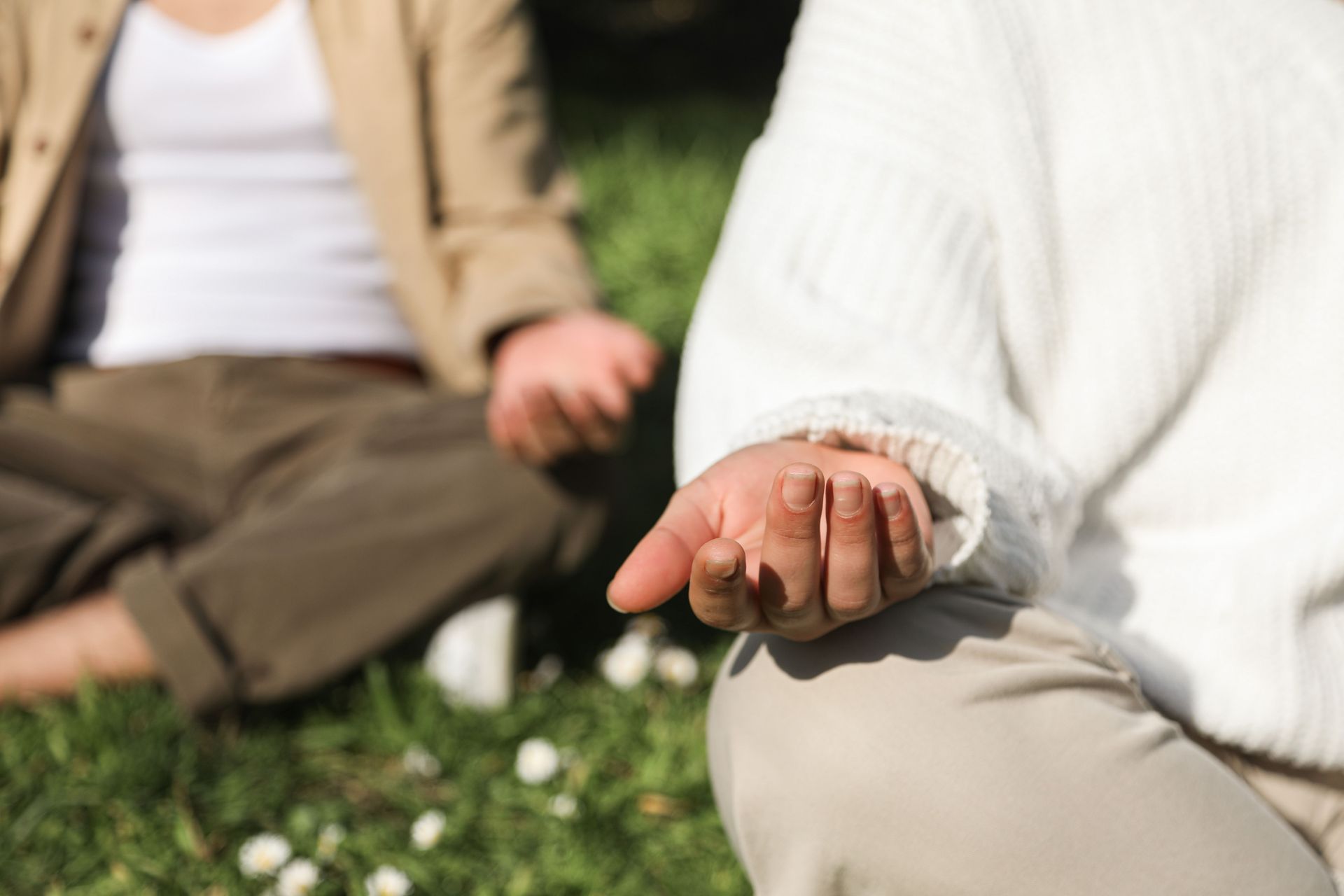 Person meditating on a yoga mat outdoors, hands in prayer pose, with candles nearby
