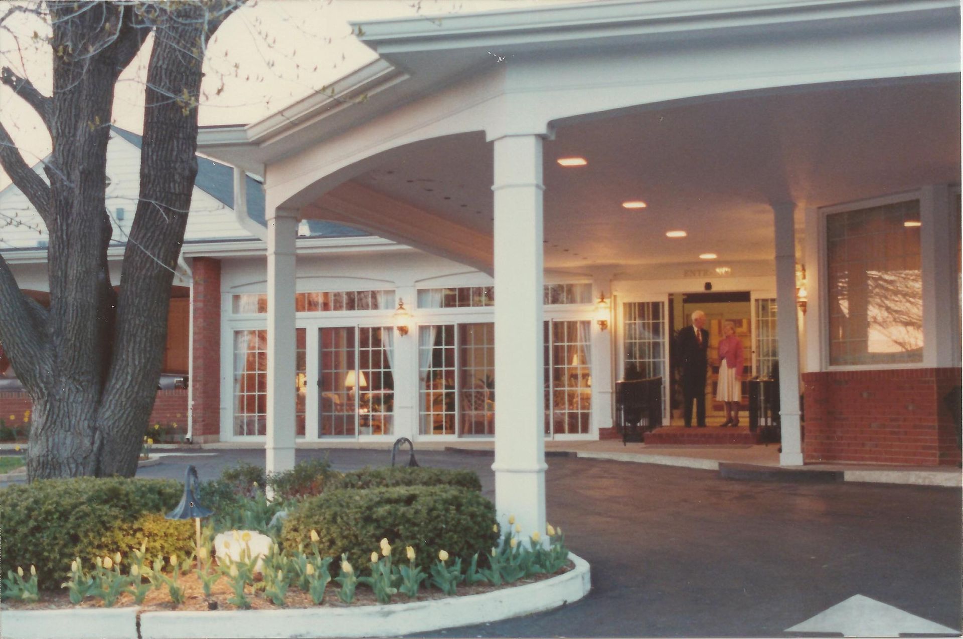 Hotel entrance with white columns, red brick, glass doors, and a covered driveway