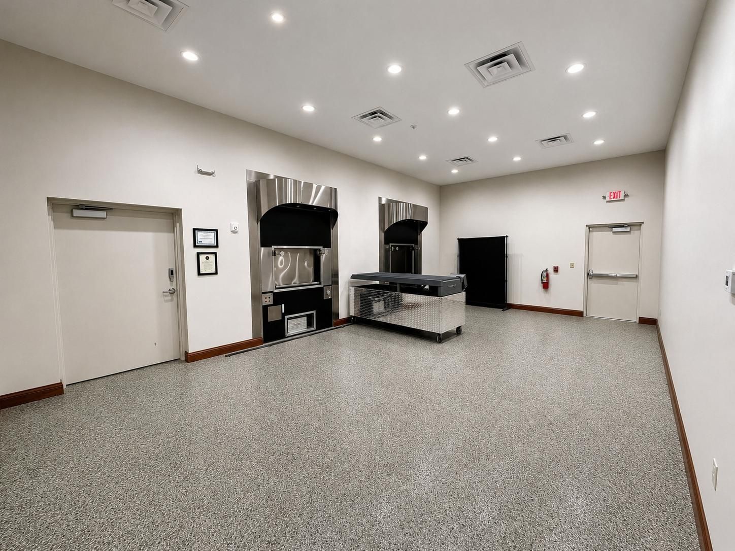 Empty banquet hall with white walls, recessed lights, and a service counter against the back wall.