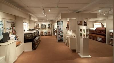 Museum exhibit gallery with antique cars, display cases, and framed artifacts in a bright room
