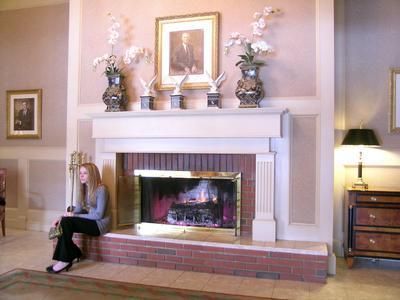 Living room fireplace with mantel decor and a seated woman reading on the left