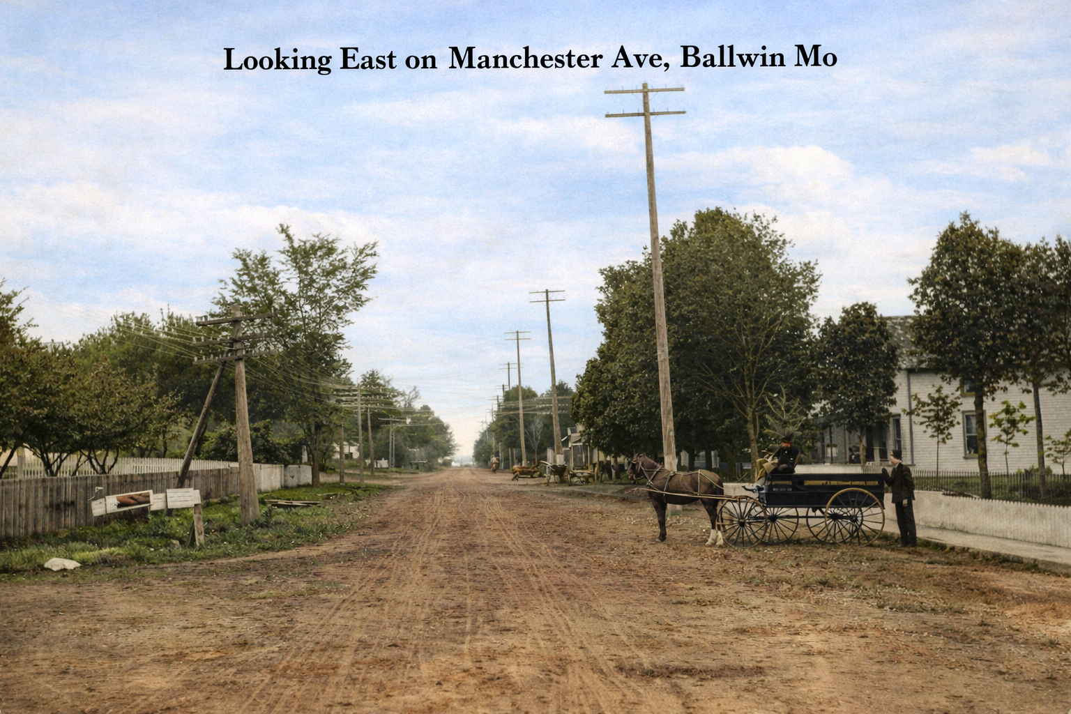 Dirt road in Ballwin, Missouri, with houses, trees, and utility poles under a blue sky.