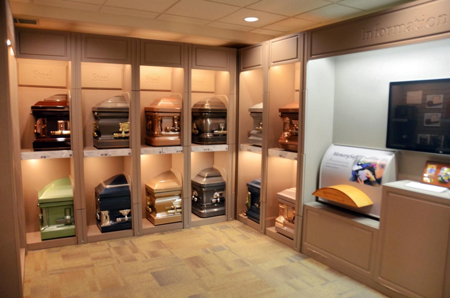 Display of assorted urns and keepsake boxes in a softly lit memorial showroom with glass-front cabinets