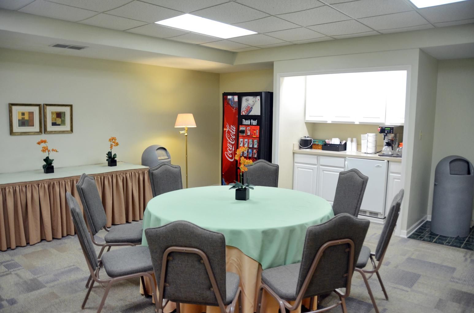 Meeting room with round table, gray chairs, and a vending machine against the wall