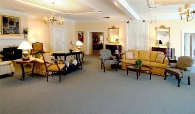 Elegant living room with beige sofas, armchairs, lamps, and a round dining table under recessed ceiling lights