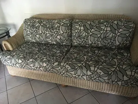 A Wicker Couch With a Patterned Cushion is on a Tiled Floor in a Living Room — Paulie's Upholstery in Edmonton, QLD
